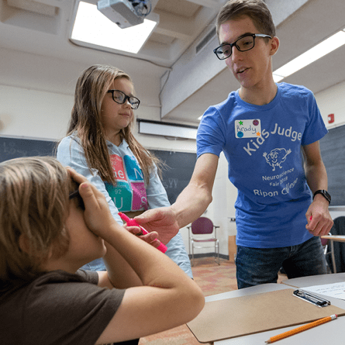 Ripon College sophomore Brady Spors teaches a pair of grade school students about the brain and five senses.