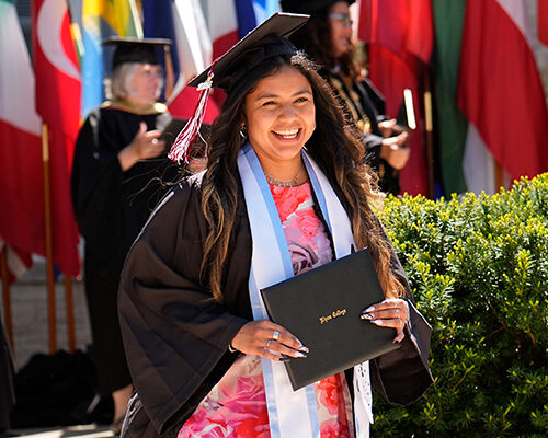 A student walks across the commencement platform with a smile