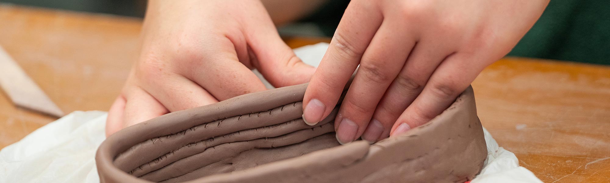 Hands pinch together clay