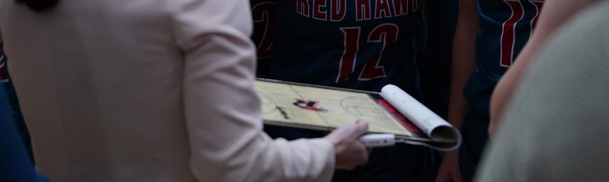 A coach and their clipboard at a Redhawks game