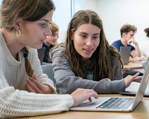 Two students work from a laptop