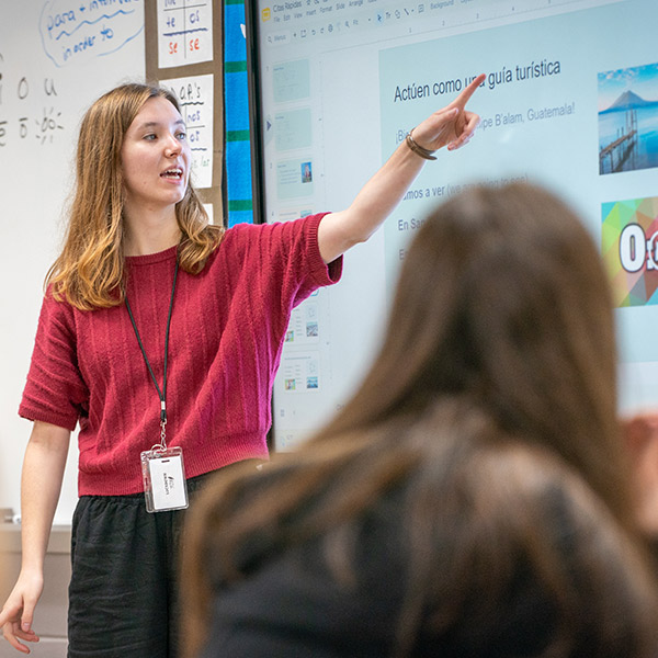 A teacher in a Spanish class points to a smart screen