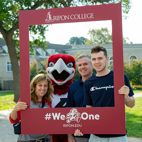 Ripon College student and his parents post with Rally the Red Hawk and Family Weekend