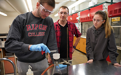 Assistant Professor of Chemistry Bryan Nell works with two students in the chemistry lab