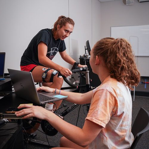 Macy Goldthorpe '26 conducts research gauging muscle activity while Kassidy Walters '23 rides a stationary bike