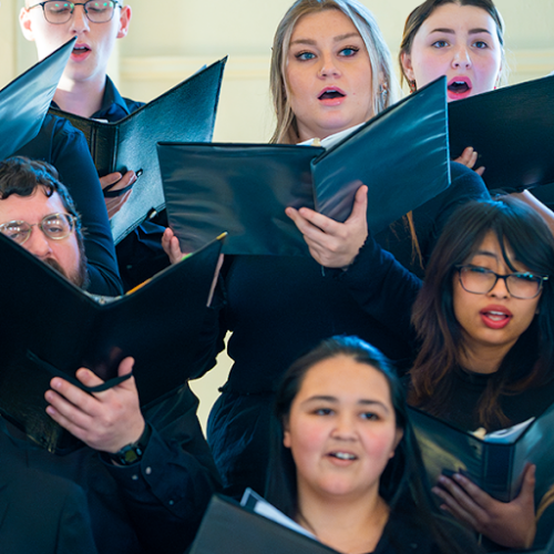 Several choir members sing from books