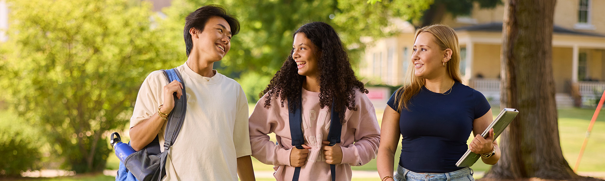 Students laugh and talk in front of the Admissions Building