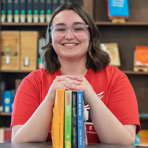 Blakeslee sitting with books in the Lane Library