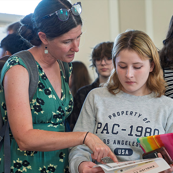 A professor helps a student at the activity fair