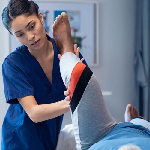A nurse bends the knee of a patient.