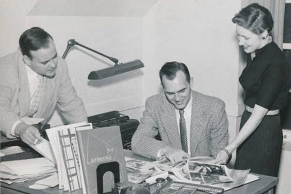 3 people pour over layouts for the yearbook