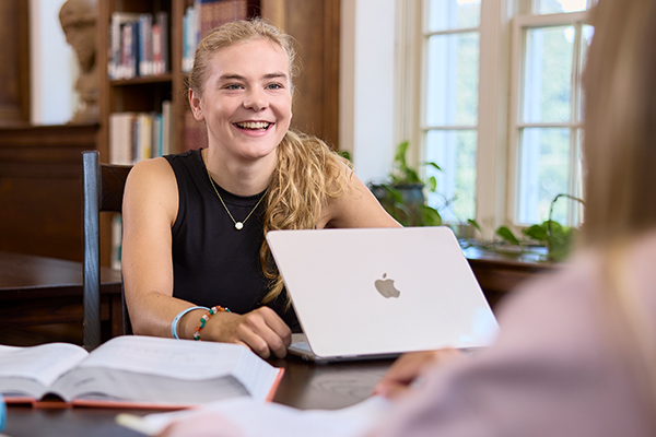 A student smiles while using a computer in Lane Library