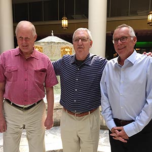 Three men stand together