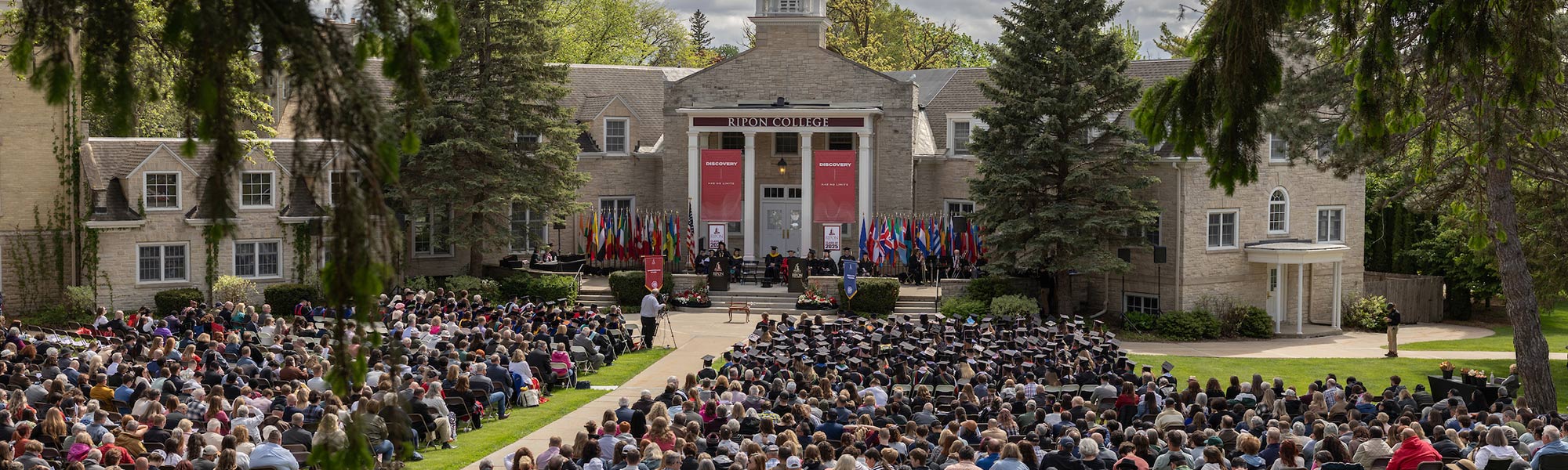 A large crowd gathers in front of Harwood Hall