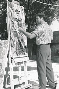 Lester works on a painting on an easel 