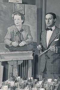 Lester in a suit and bow tie stands next to a portrait