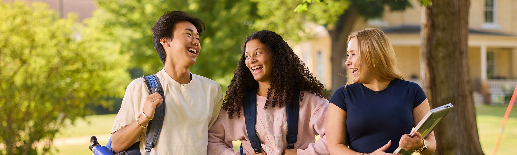 3 students laugh and talk in front of Evans Hall