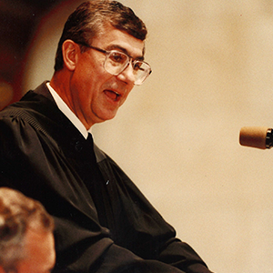 Wilcox speaks in Judge robes behind podium