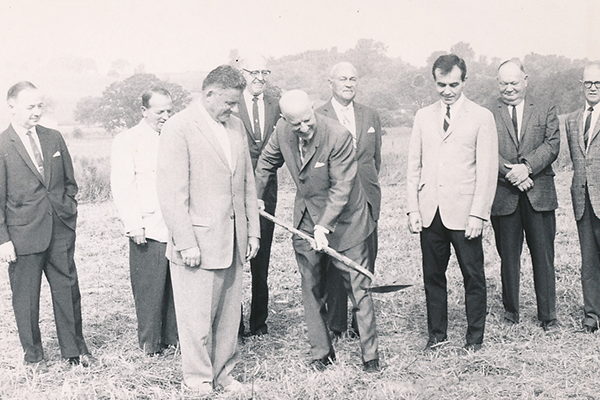 A group of men shovel to break ground
