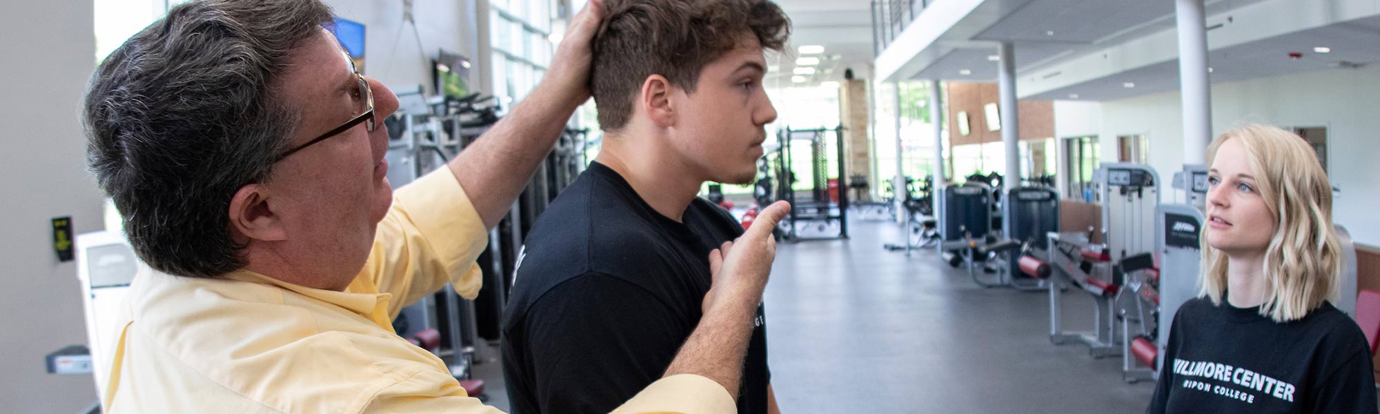 A teacher guides a students head forward