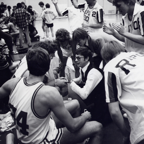Coach sitting with players on basketball court.