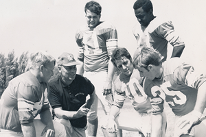 Coach Storzer kneels with team and coaches.