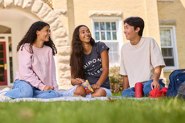 Three students share a laugh in front of Smith Hall