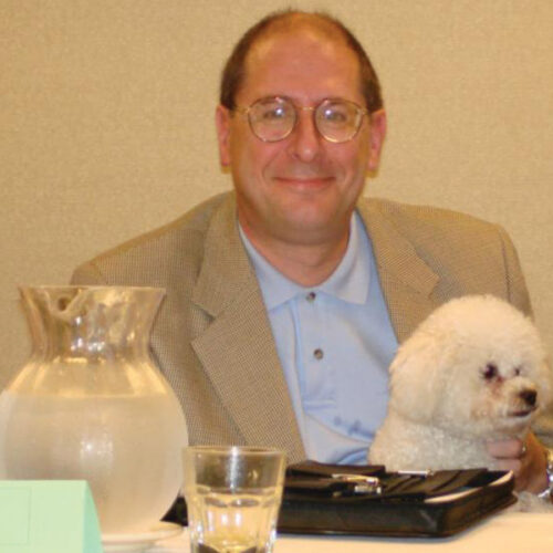 A man sits happily with a small dog.