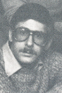 A man in dark glasses looks to the camera