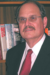 A person in a suit and tie in front of a small library