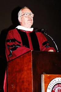 Doug speaking at a podium in red Ripon garb