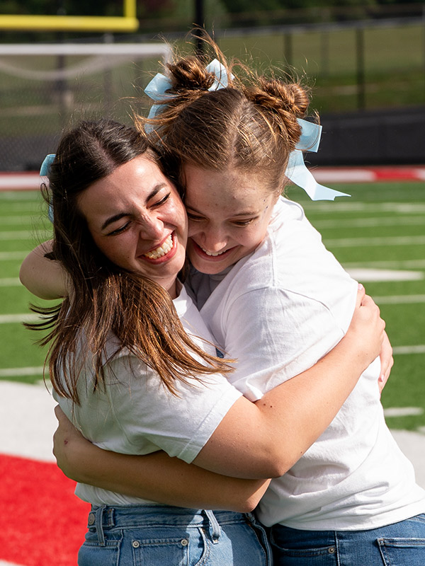 A girl hugs her sorority sister aggressively
