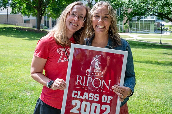 Two alumni hold a Class of 2002 sign during Alumni Weekend.
