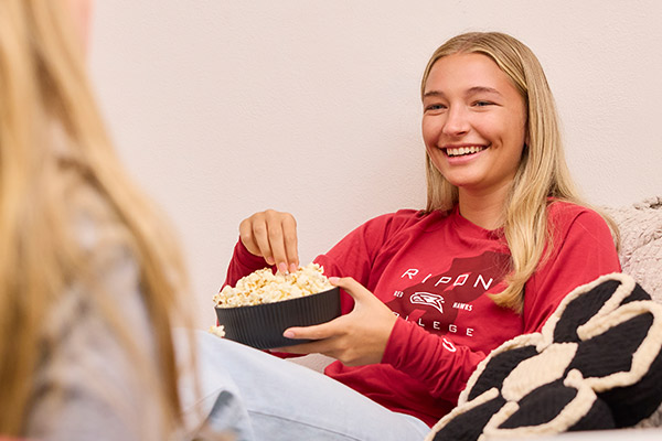 A girl eats popcorn in a comfortable chair.