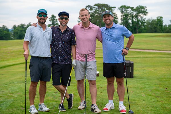 Four friends in stand arm in arm on the golf green.