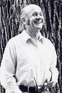 Jerry stands in front of a large tree and smiles