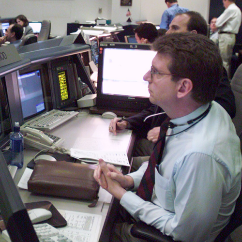 A man sits with many monitors in a NASA building