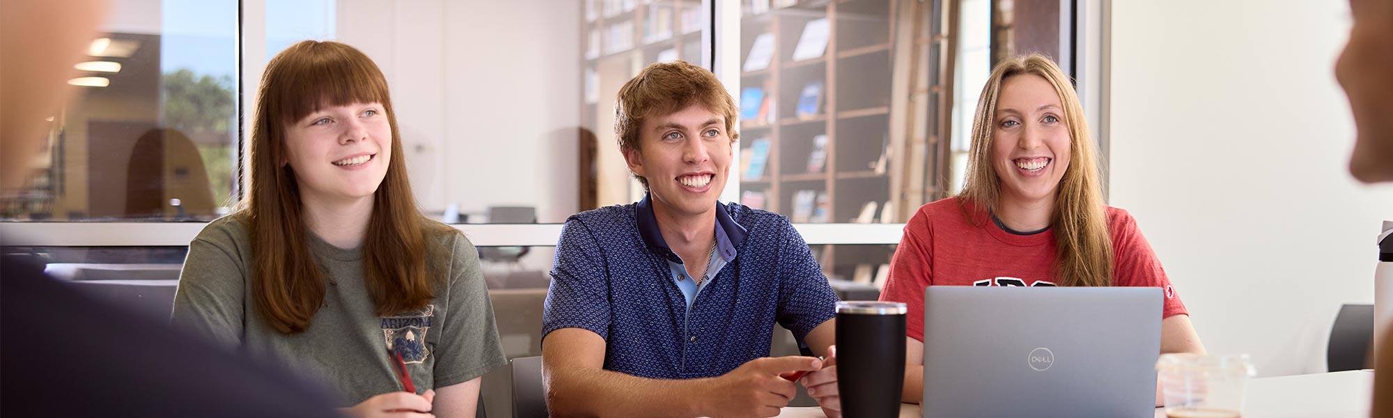 Three students smile on one side of a table in Franzen Learning Center