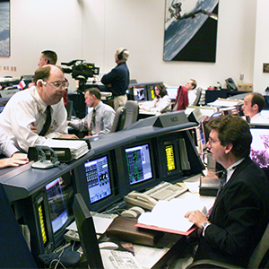 Bantle sits in front of many computer screens in a Nasa Building