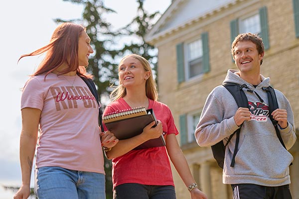 Three students laugh as they walk through the residence halls