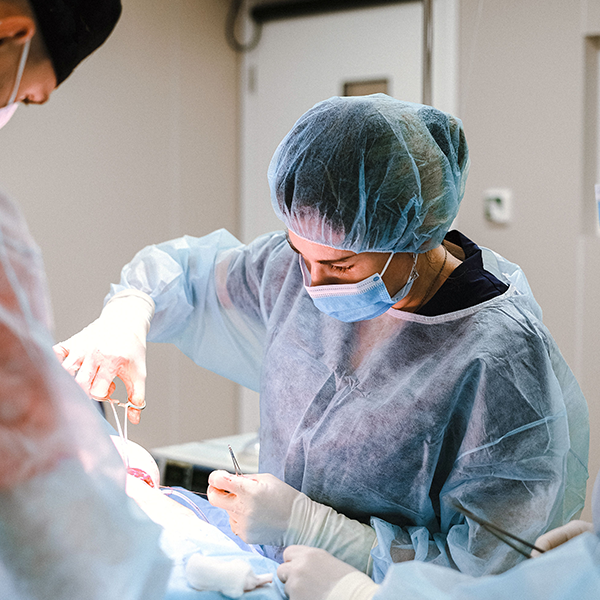 A surgeon in scrubs works on a patient.
