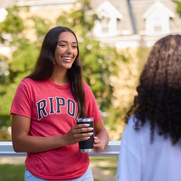 Student in red Ripon shirt drinking coffee