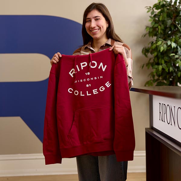 A student in the admissions office holds up a new sweatshirt