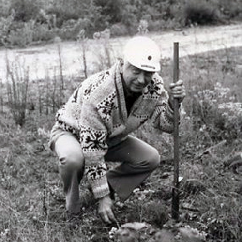 Trainer with helmet a stick standing in a field