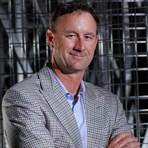 Brad in a blazer smiles for portrait.