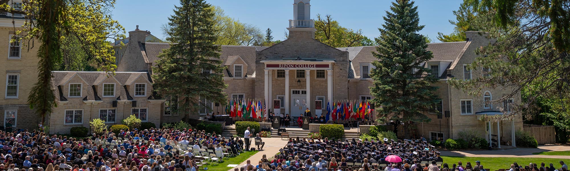 A large group gathers for Commencement in front of Harwood Hall
