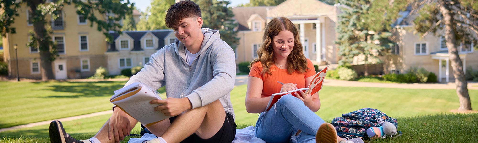2 students enjoy time on the lawn in front of Harwood Hall