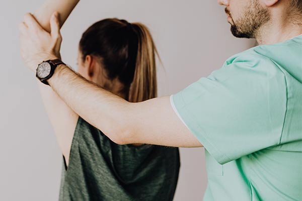 A therapist helps a patient raise their arm