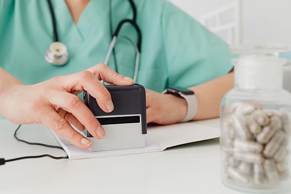 A pharmacist stamps a prescription- photo by kaboom pics on pexels