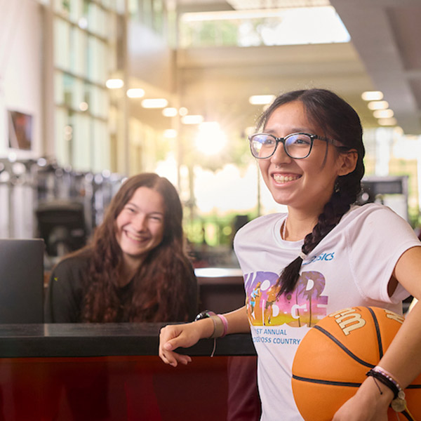 students standing at the front desk of the Willmore Center with a smile